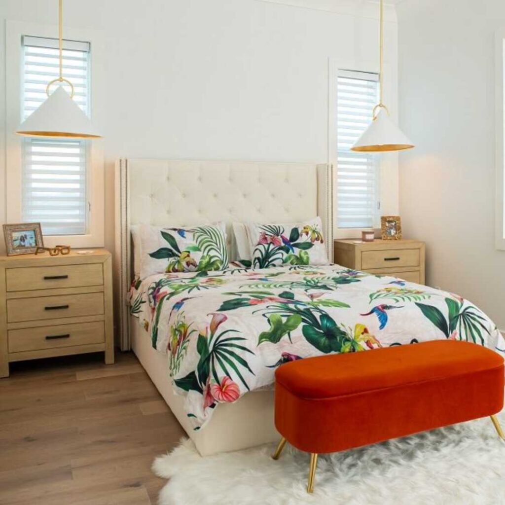 A bed with a floral print bedding and a red ottoman