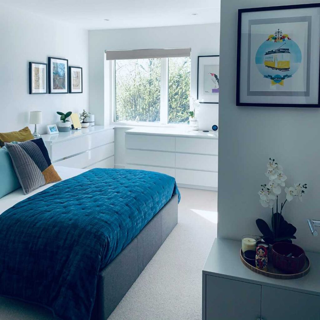 A bedroom with a blue bed and white cabinets
