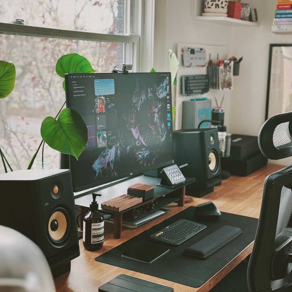 A desk with a computer and speakers in an earthy tones home office