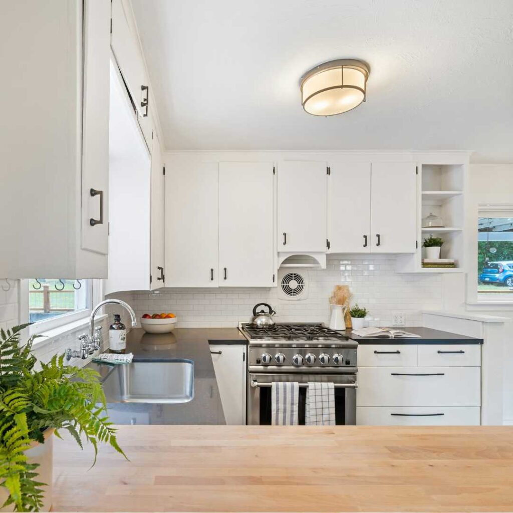 A kitchen with white cabinets and a plant