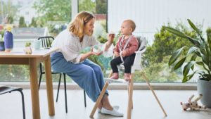 a mommy feeds her baby on high chair